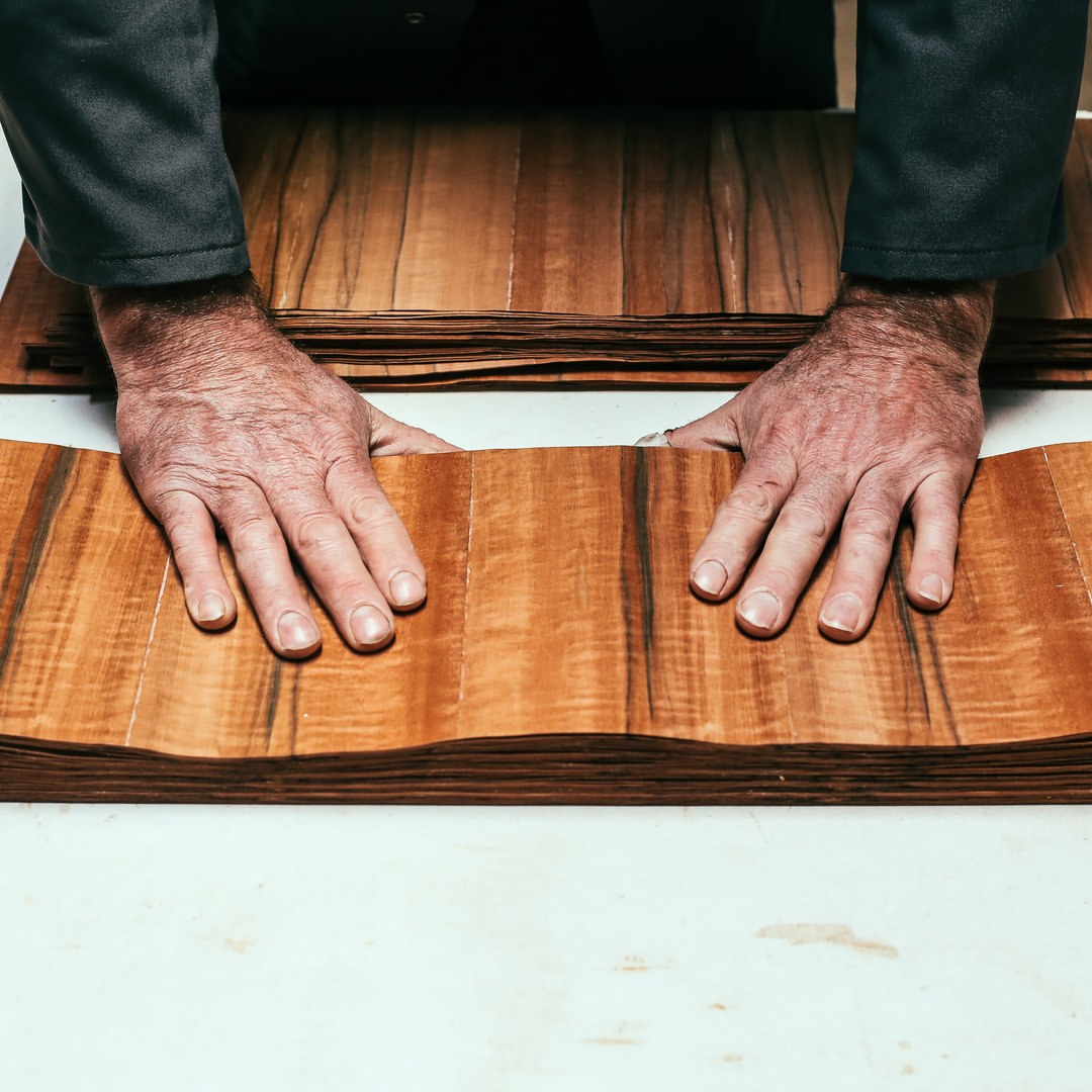 Mains d'artisan sur des feuilles de bois précieux destinées aux montures Shelter